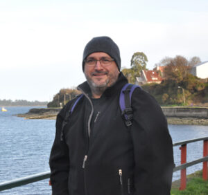 Headshot of faculty member Andres Barria outside by body of water.