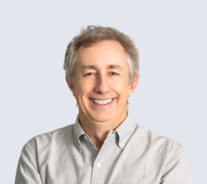 Formal headshot of faculty member Michael MacCoss. Michael is wearing a button up shirt in front of a light grey background.