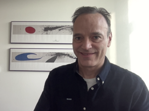 Formal headshot of faculty member Horacio de la Iglesia. Horacio is wearing a button up shirt with two framed art prints in the background.