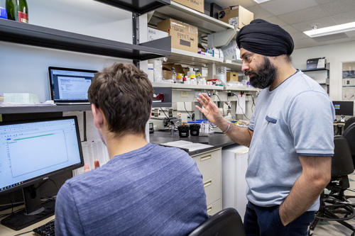 MCB faculty member speaking with MCB student in front of computer in lab space.