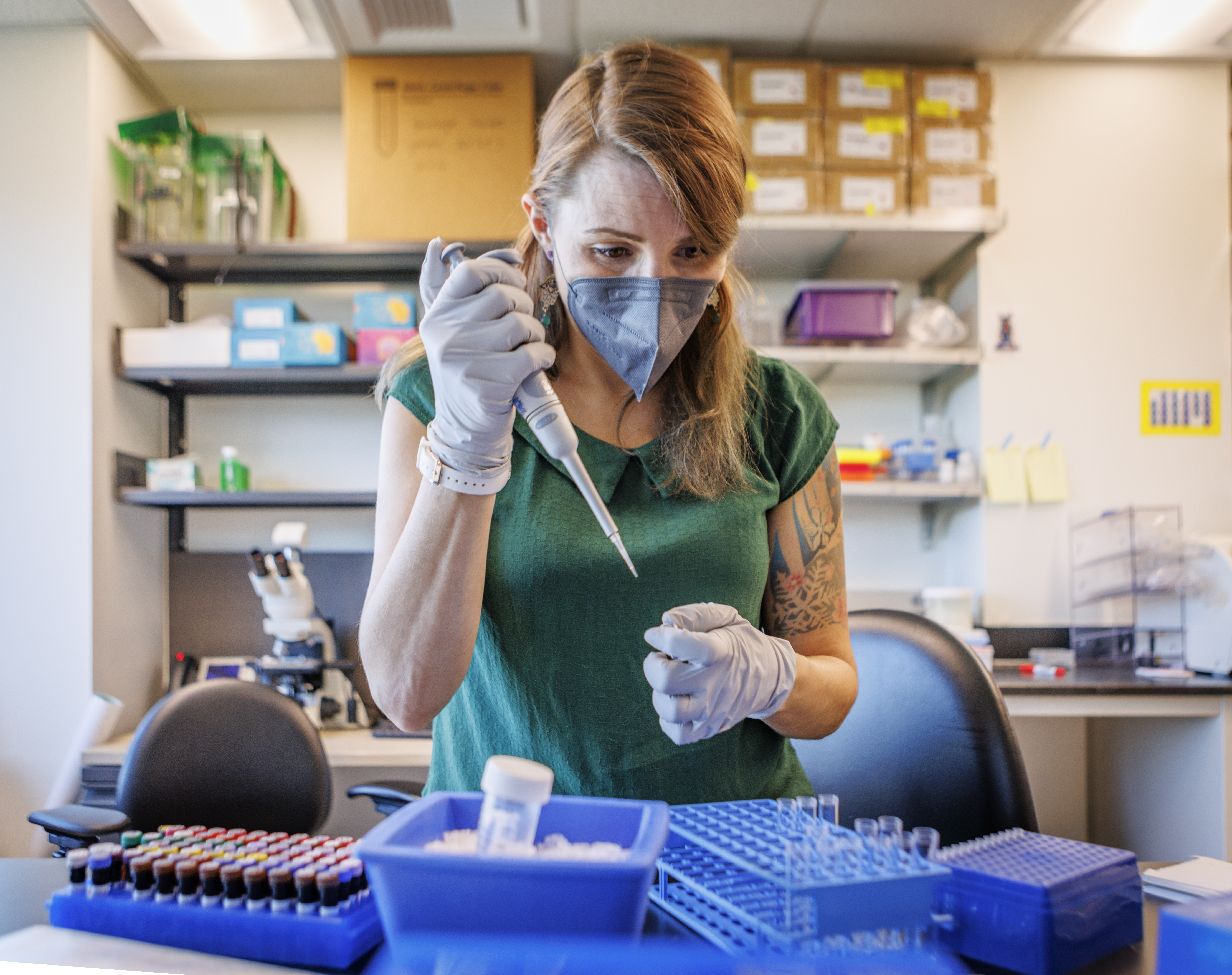 MCB student wearing a mask conducting work in lab with pipette.