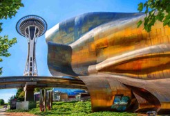Image of Seattle Center with Space Needle in the background, the Museum of Pop Culture in the foreground, and the Seattle Monorail tracking running in between the two structures.