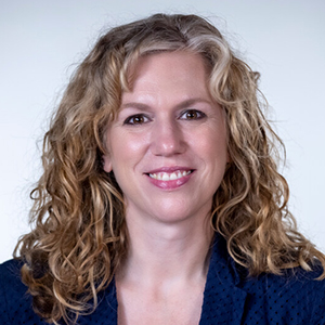 Professional headshot of MCB staff member Andrea Brocato with light grey background.