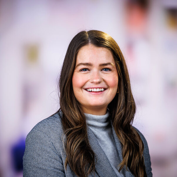 Professional headshot of MCB staff member Mel Leavens with a multi-colored background.